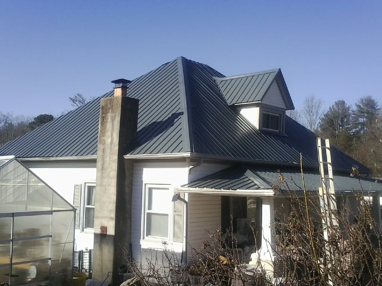 Dark blue standing seam metal roof on a white farmhouse with dormer — Slate & Tile Roof Repair by Roofing Brothers in Swoope