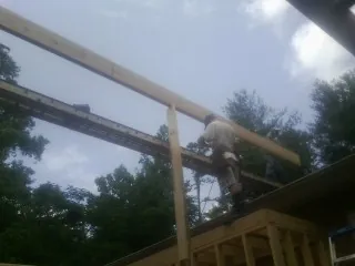 Carpenter setting a ridge beam over a new addition frame — Ice Dam Removal by Roofing Brothers in Swoope