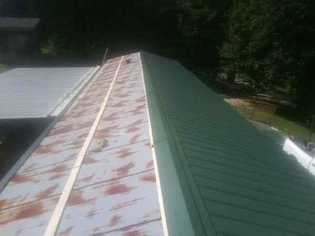 Old rusted panels beside newly installed green metal roofing — Wind Damage Roof Repair by Roofing Brothers in Swoope