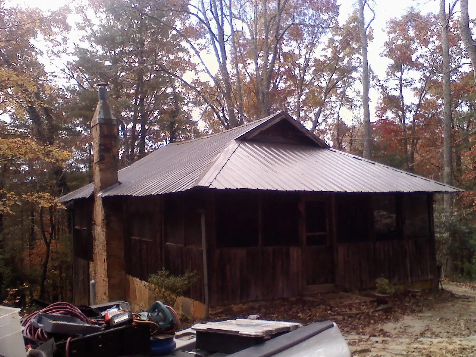 Brown metal hip roof on an old cabin with a stone chimney in Swoope