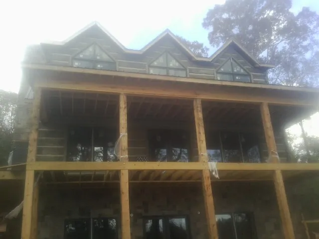 Dormers and porch framing on a large log home under construction — Roof Coating work by our crew in Swoope