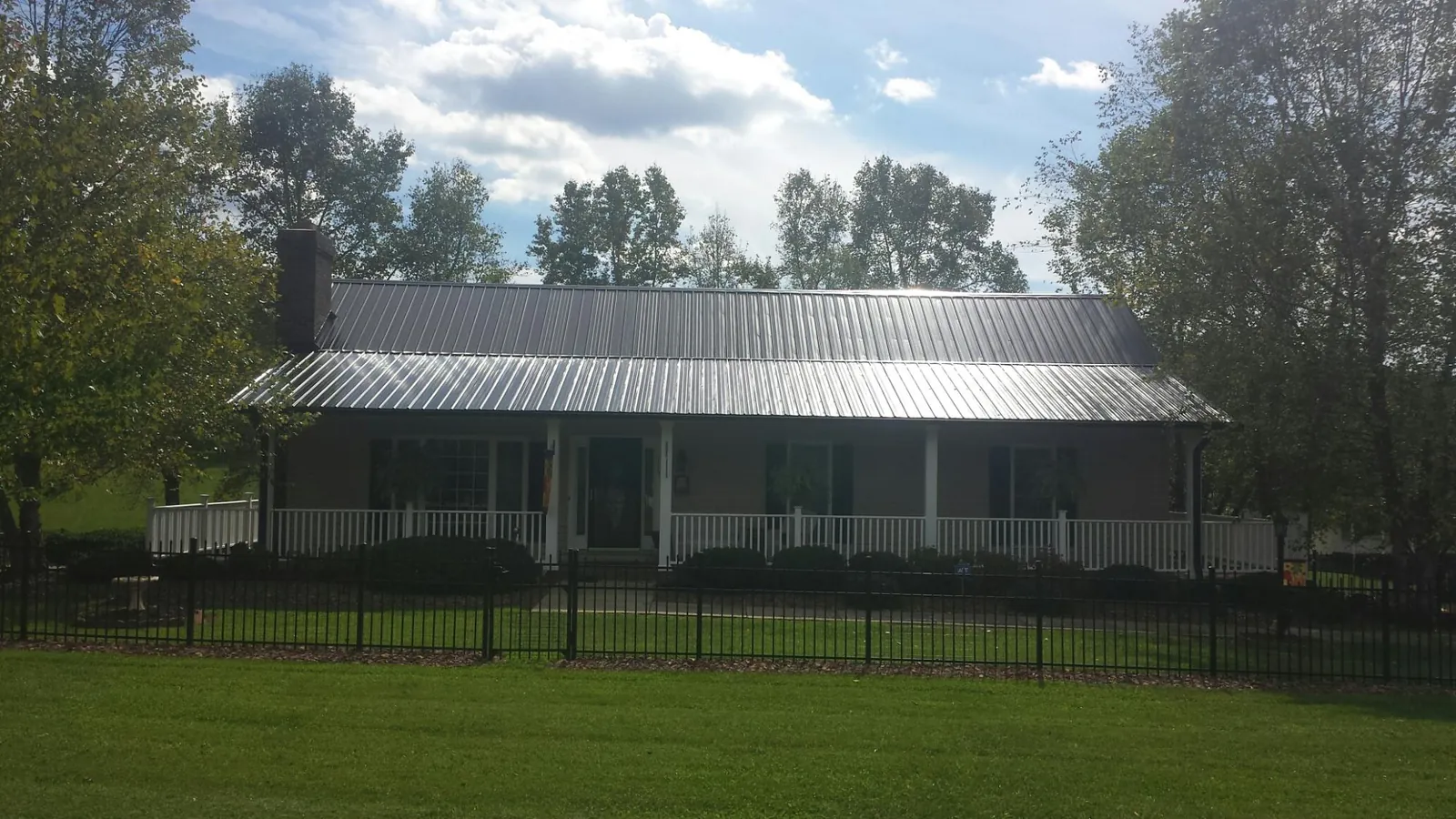 Gray metal roof on a brick ranch with a full width front porch — Gutter Guard Installation work by our crew in Swoope
