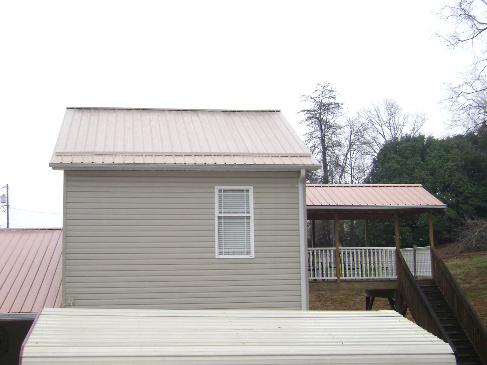 Tan metal roofs on a two story addition and attached porch, from a Roof Replacement job in Swoope