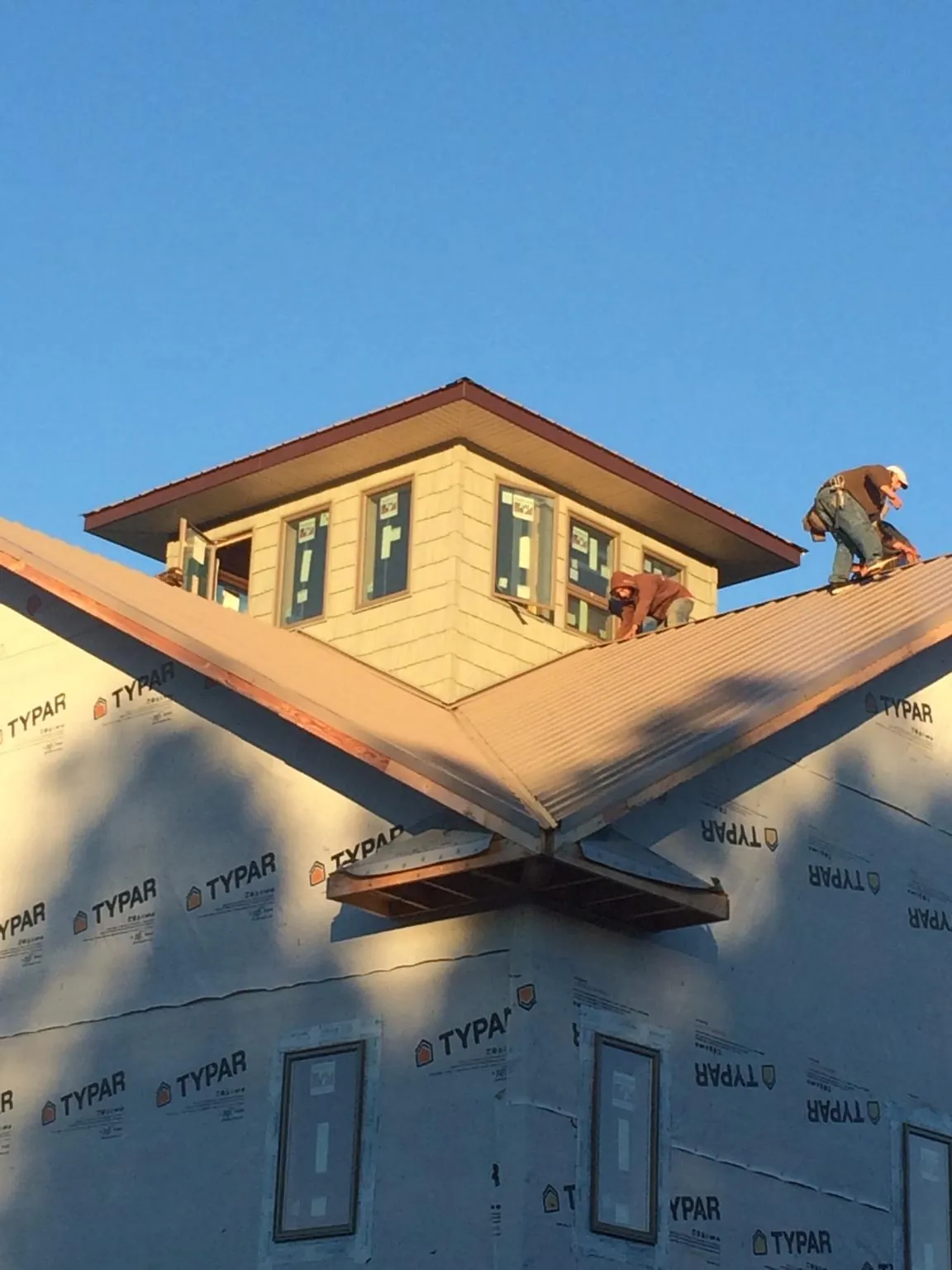 Roofers working around a rooftop cupola on a new metal roof at sunset — Roof Waterproofing in Swoope by Roofing Brothers